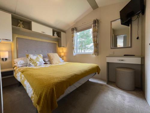 a bedroom with a bed with a yellow bedspread at Seton Sands Caravan Near Edinburgh & North Berwick in Port Seton