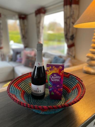 a bottle of wine on a plate on a table at Seton Sands Caravan Near Edinburgh & North Berwick in Port Seton