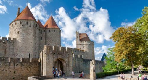 ein großes Schloss mit Leuten, die draußen stehen in der Unterkunft La Maison du Roi Arthur in Carcassonne