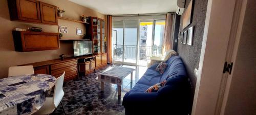 a living room with a blue couch and a table at Apartamento 1 línea de playa + Parking! Salou in Salou