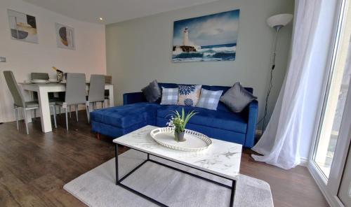 a living room with a blue couch and a table at Margam's Alvington House for Business Travellers, Relocator or Families with FREE Parking, High Speed Internet and fully equipped kitchen 