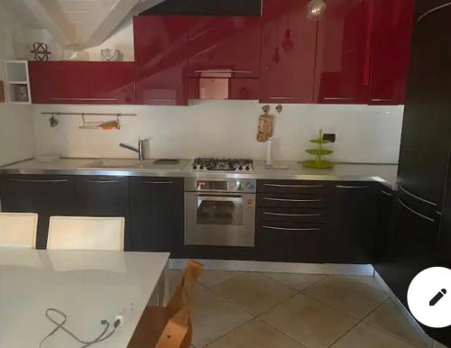 uma cozinha com armários vermelhos e um forno com placa de fogão em Stupendo appartamento em Mozzo