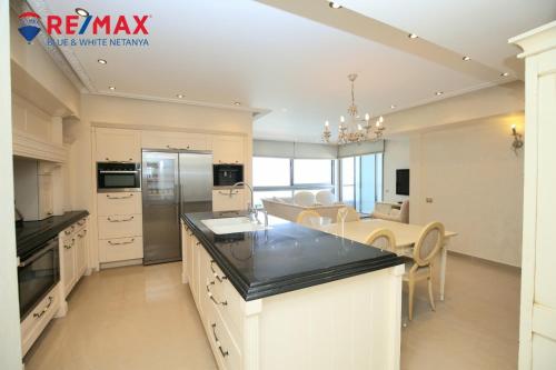 uma cozinha com armários brancos e uma sala de jantar em פנינה על הים em Netanya