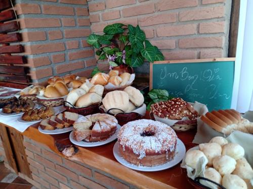 a table filled with different types of pastries on plates at Pousada Refugio Sol e Brisa in São Bento do Sapucaí