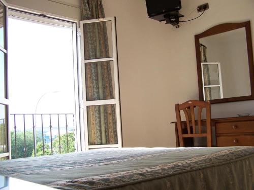 - une chambre avec un lit, un miroir et une fenêtre dans l'établissement Hostal Adrian, à Pizarra
