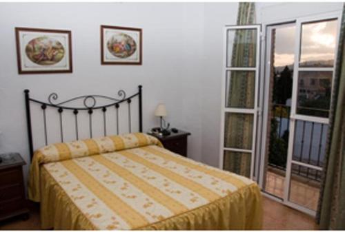 una camera con un letto e una grande finestra di Hostal Adrian a Pizarra