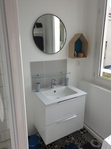 ein weißes Badezimmer mit einem Waschbecken und einem Spiegel in der Unterkunft Meublé très cosy à proximité de toutes commodités in Rouen