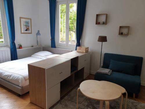 Schlafzimmer mit einem Schreibtisch, einem Bett und einem Stuhl in der Unterkunft Meublé très cosy à proximité de toutes commodités in Rouen