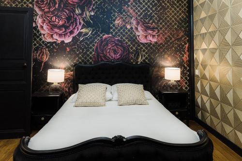 - un lit avec deux oreillers dans une chambre avec un mur fleuri dans l'établissement LWHouse, à Palluau