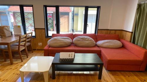 uma sala de estar com um sofá vermelho com almofadas em Guesthouse Danran - Vacation STAY 96856v em Beppu