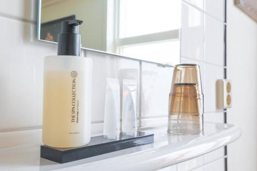 a bathroom shelf with a bottle of shampoo and a soap dispenser at Hotel Fase Fier Eten en Drinken in Castricum