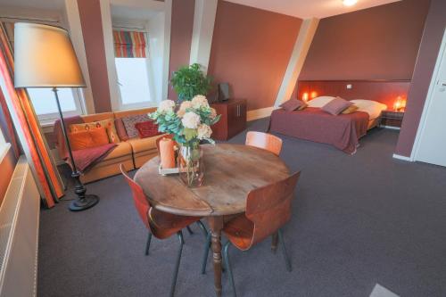 a living room with a table with flowers on it at Hotel Fase Fier Eten en Drinken in Castricum