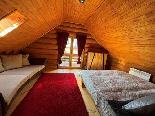 a attic bedroom with a bed and a red rug at Zrub Hanesy in Donovaly
