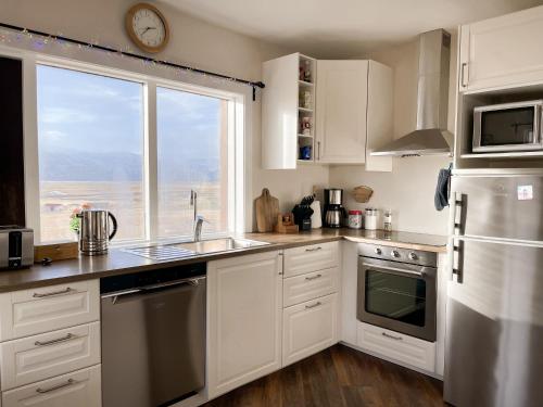 a kitchen with white cabinets and a large window at Setberg Guesthouse in Nesjum