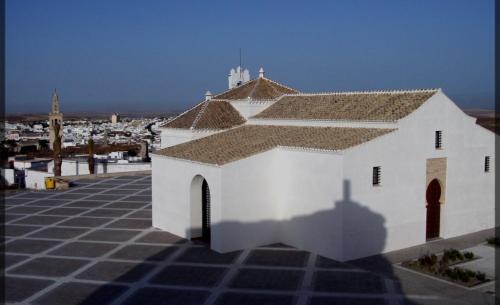 a white building with a shadow on a tile floor at Ocón 2 in Lebrija