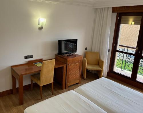 a hotel room with a desk and a television and a bed at Gran Hotel Liber & Spa Playa Golf in Noja