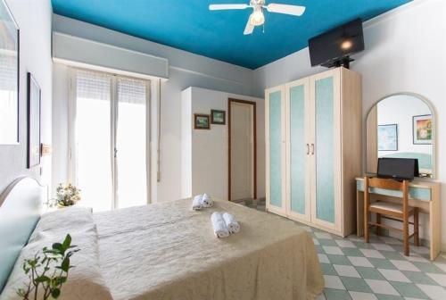 - une chambre avec un grand lit et un plafond bleu dans l'établissement Hotel Locarno, à Cattolica