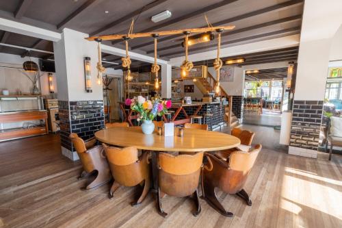 una sala da pranzo con tavolo e sedie in legno di Hotel Fase Fier Eten en Drinken a Castricum