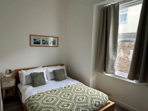 a bed in a bedroom with a window at Carmen Sylva Llandudno Beach ground floor Flat in Llandudno