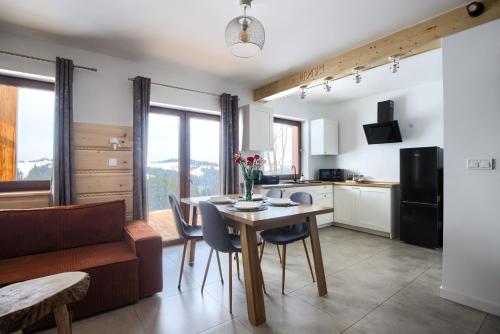 een keuken en eetkamer met een tafel en stoelen bij WierchoHouse - domek z jacuzzi in Groń