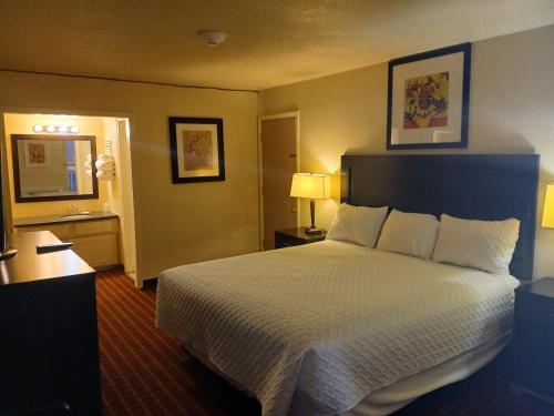 una habitación de hotel con una cama grande con sábanas blancas en 76 Family Inn, en Branson