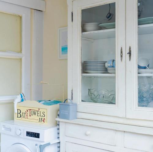 a white cabinet with plates and dishes in it at Beach House in Whitley Bay