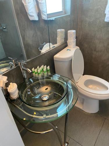 a bathroom with a glass sink and a toilet at M HOTEL in Miami Beach