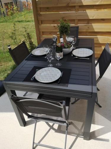 - une table noire avec des assiettes et des verres à vin dans l'établissement Maison Jasmin-Citrus, à Saint-Valery-sur-Somme