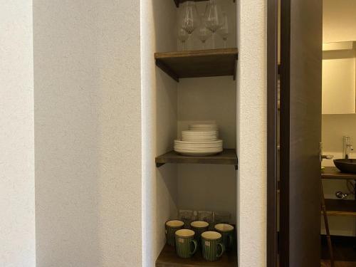 eine Pantryküche mit Tellern und Gläsern auf einem Regal in der Unterkunft Kobe Motomachi Roji Building - Vacation STAY 16195 in Kōbe
