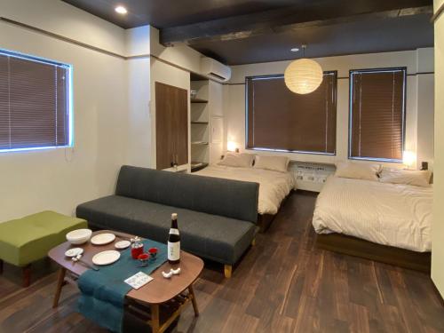 una camera con due letti, un divano e un tavolo di Kobe Motomachi Roji Building - Vacation STAY 16195 a Kobe