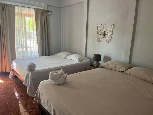 two beds in a room with a butterfly on the wall at Cabinas Bahía Uvita - Marino Ballena National Park Lodge in Uvita