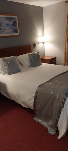 een groot wit bed in een hotelkamer bij The Emmbrook Inn Hotel in Wokingham