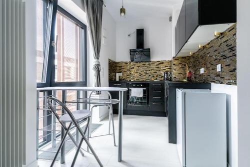 a kitchen with black cabinets and a table and chairs at UrbanNest_Krochmalna in Warsaw