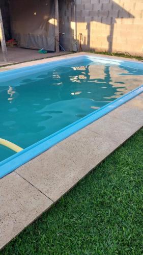una piscina azul junto a una acera y césped en Casa con pileta Matheu en Junín