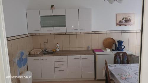 uma cozinha com armários brancos, um lavatório e uma mesa em Appartment Utjeha em Utjeha