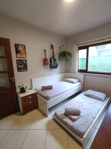 een slaapkamer met 2 bedden en 2 gitaren aan de muur bij Quarto Felicidade Cabeçudas in Itajaí