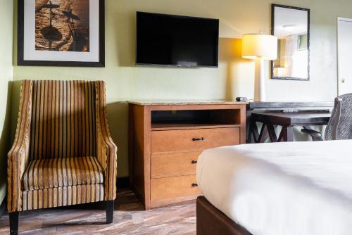 a hotel room with a bed and a chair and a desk at The Buena Park Hotel & Suites in Buena Park