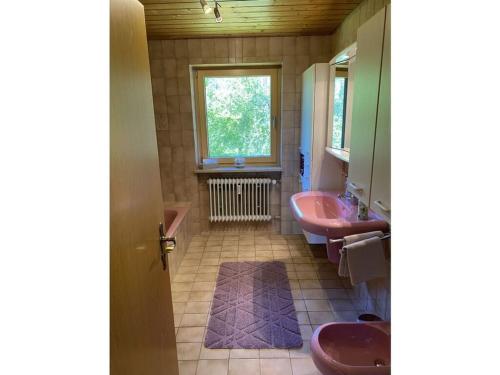 uma casa de banho com 2 lavatórios cor-de-rosa e uma janela em Allgäu Glück Simon em Argenbühl