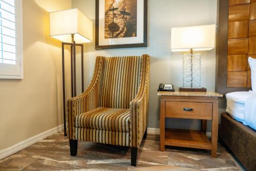 a hotel room with a chair and a night stand at The Buena Park Hotel & Suites in Buena Park