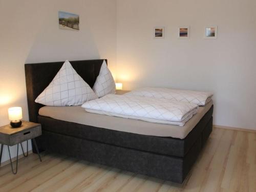 een slaapkamer met een groot bed met witte lakens bij Bungalow Huus Seerose in Krummhörn