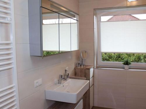een badkamer met een wastafel en 2 ramen bij Bungalow Huus Seerose in Krummhörn