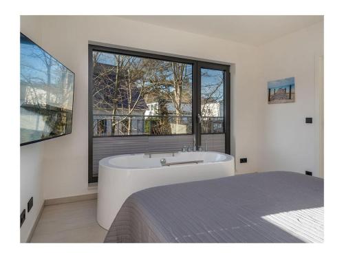 a bedroom with a tub and a bed and a window at Holiday Apartment 1 Comfortable Vacation Home in Juliusruh