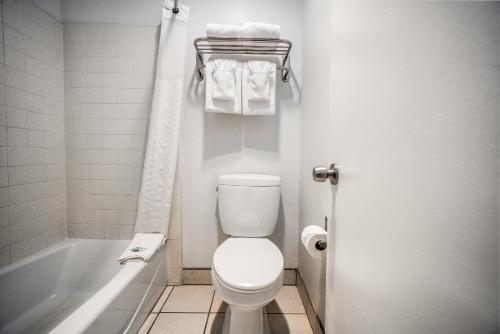a bathroom with a toilet and a bath tub with towels at The Buena Park Hotel & Suites in Buena Park