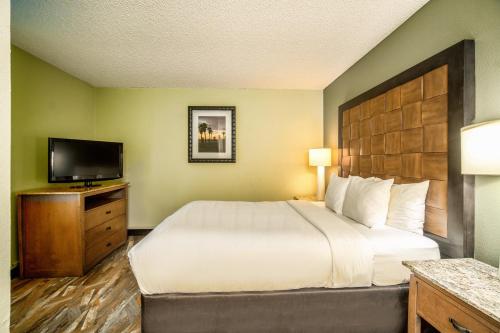 a hotel room with a bed and a flat screen tv at The Buena Park Hotel & Suites in Buena Park