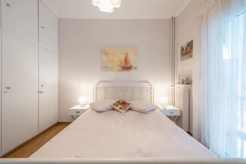 アテネにあるCozy Athens Apartmentの白いベッドルーム(大きな白いベッド1台、テーブル2台付)