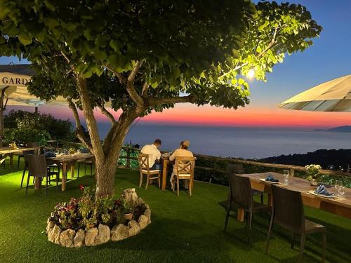 two people sitting at a table under a tree at Agriturismo del Sole in Anacapri