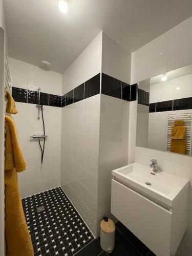 La salle de bains est pourvue d'un lavabo blanc et de carrelage noir et blanc. dans l'établissement Maison centre ville Ploërmel avec terrasse, à Ploërmel