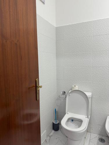 a bathroom with a toilet and a wooden door at Torre suit property in Torre da Marinha