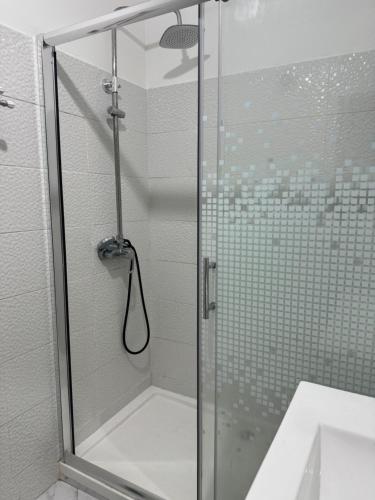 ducha con puerta de cristal y lavamanos en Torre suit property en Torre da Marinha