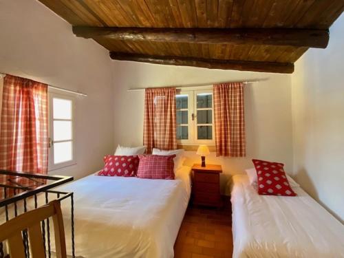 1 dormitorio con 2 camas y almohadas rojas en Les Calades, en Lédenon